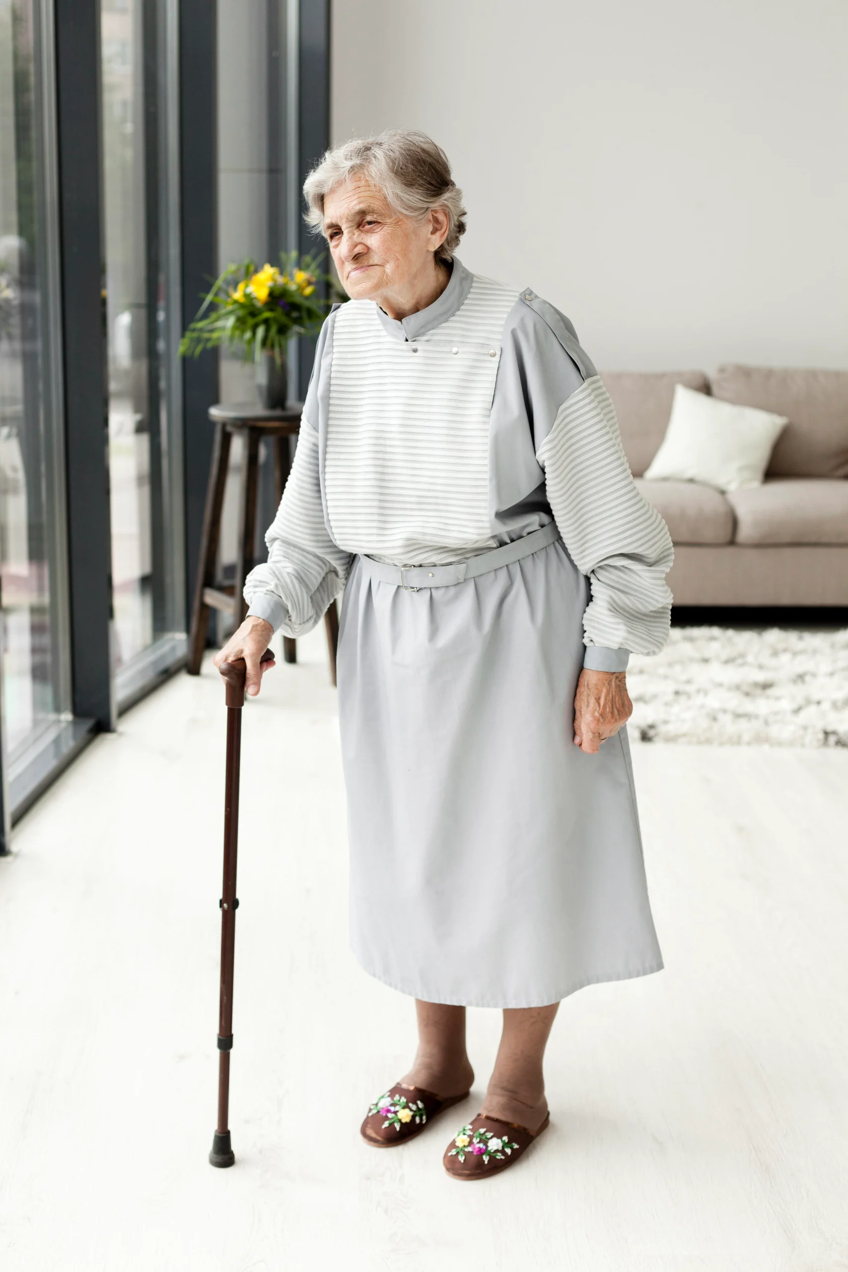 Elderly Woman Using a Walking Cane for Mobility Support in a Modern Home Setting
